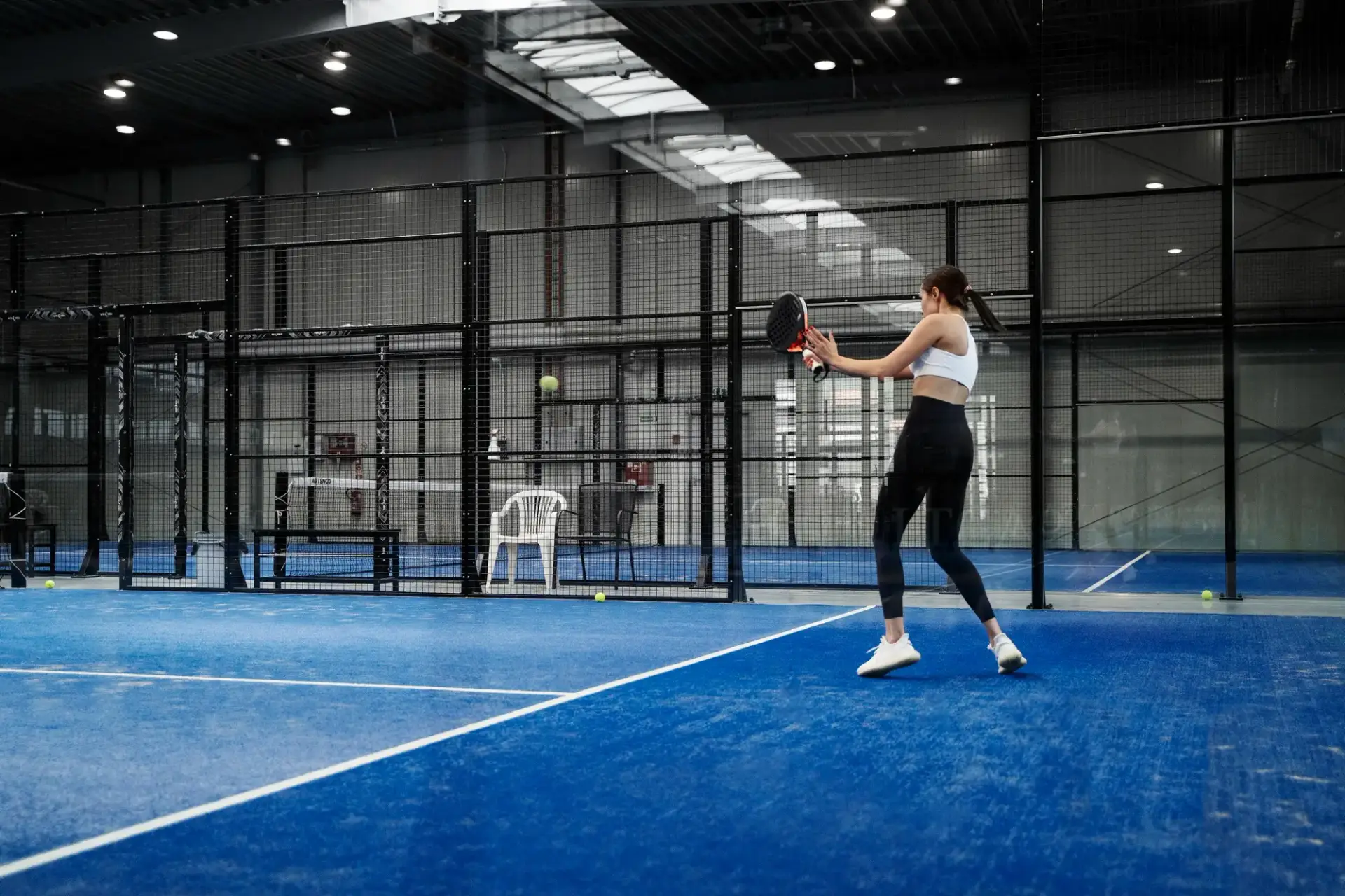 Spielerin beim Padel auf blauem Indoor-Court